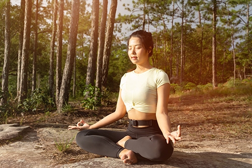 woman meditating in forest