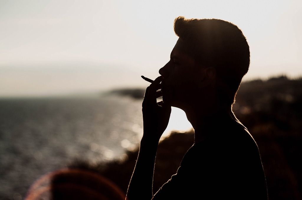 A man smokes weed outside at sunset.