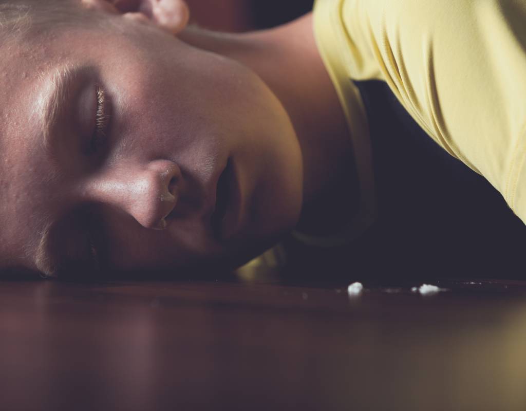 Young guy with his head on a table after snorting too much ketamine and stuck in a k-hole.